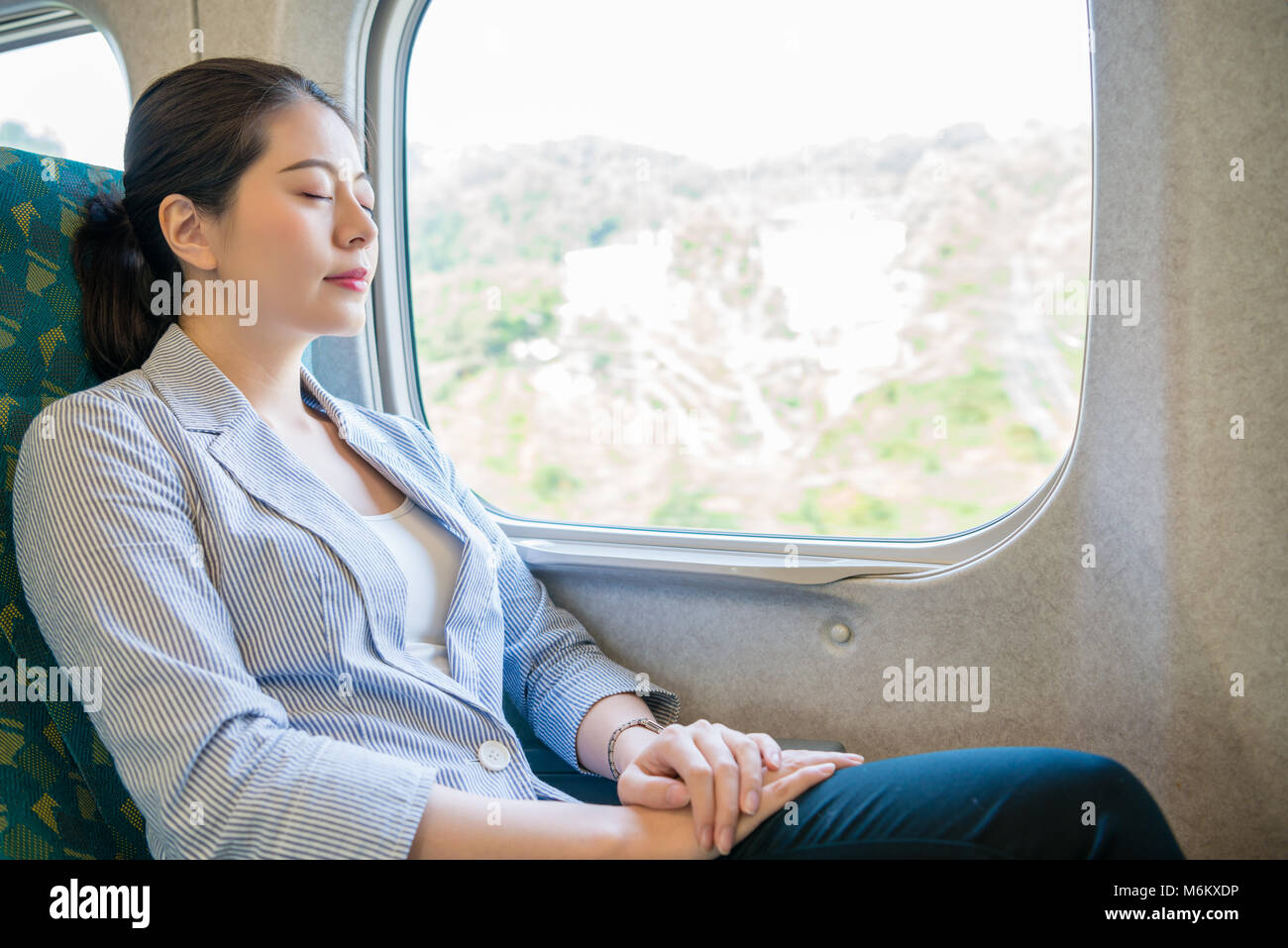 Hart arbeiten, schöne asiatische Business woman einen erholsamen Schlaf auf den fahrenden Zug für Ihre künftige Reise nehmen. Stockfoto