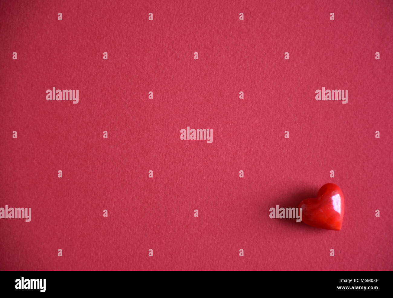 Kleine rote Liebe Herz Pebble Stone gegen einen einfachen Hintergrund Stockfoto