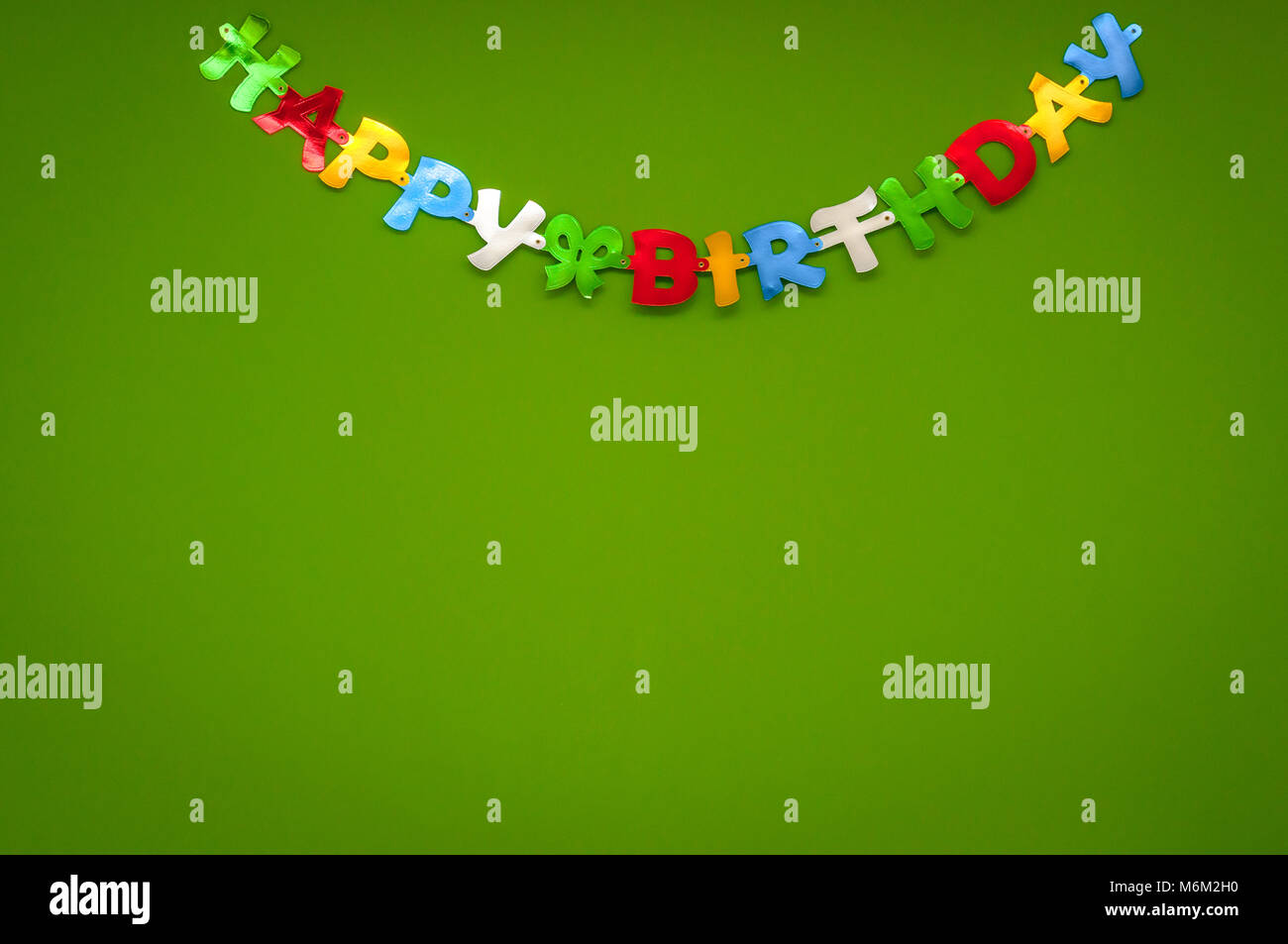 Bunte fröhliche Happy Birthday gruss Banner auf einer grünen Wand in einer Feier und Party Konzept. Stockfoto