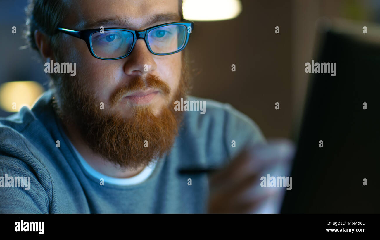 Begabte junge Concept Artist Zeichnung auf einem Digital Pen Display Tablet beim Sitzen an seinem Arbeitsplatz in Loft Büro. Spät in der Nacht. Stockfoto
