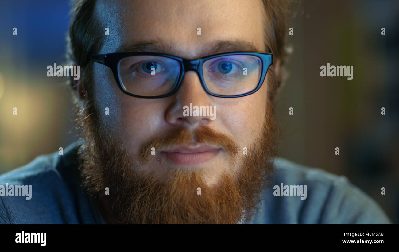 Nahaufnahme von einem jungen Bartgeier kreativen Mann mit Brille sieht lächelnd in die Kamera. Stockfoto