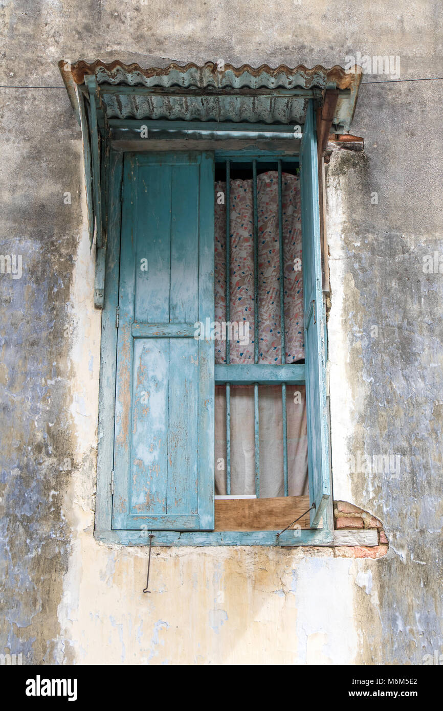 Ein geöffnetes Fenster mit Gitter und ein Blech Dach in der Fassade eines alten Hauses, Penang, Malaysia. Stockfoto