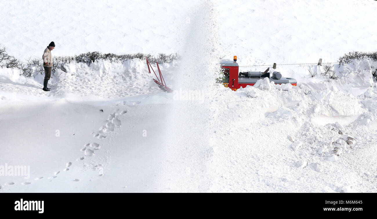 Ein Hausbesitzer wacht über eine Schneefräse, wie es die Straße, die zu einem kleinen Weiler führt, die seit Donnerstag in Parkhead in der Nähe von Kirkoswald, Cumbria blockiert wurde genehmigt. Stockfoto