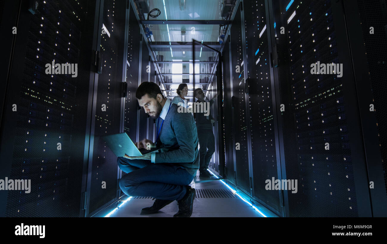 IT-Techniker arbeiten am Laptop in großen Data Center voll von Rack-servern. Mehrere Leute arbeitet bei Data Center gleichzeitig. Stockfoto