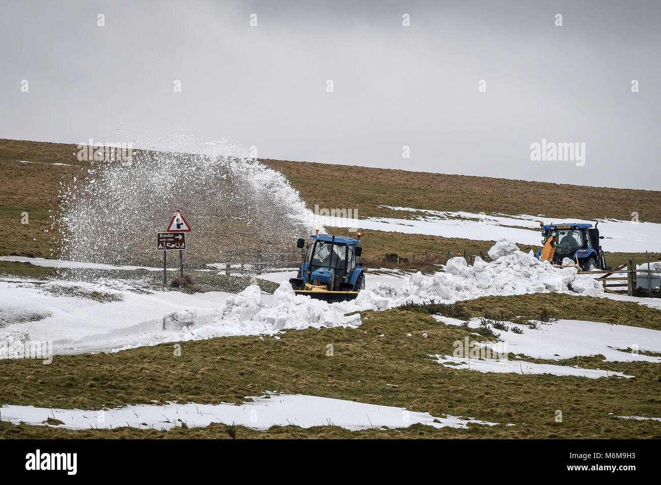 Landmaschinen ist räumen Schnee von einem Abschnitt der A 39 in Porlock Hill, in der nähe von Lynton, Exmoor, nach starken Schneeverwehungen das betroffene Gebiet und schnitt Lynton Dorf. Stockfoto