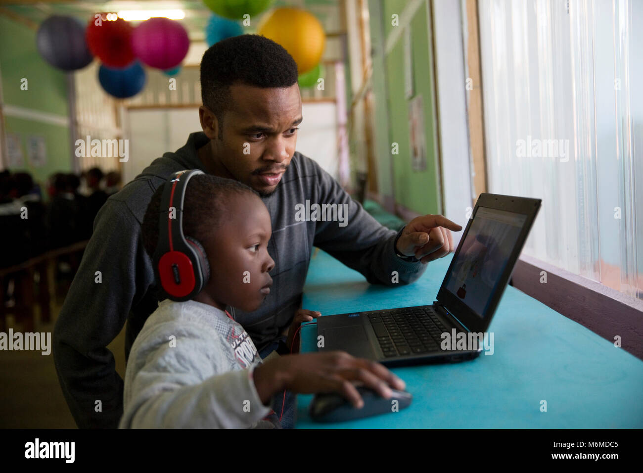 Lehrer helfen eine Schule junge Kind auf einem Laptop in der Klasse Stockfoto