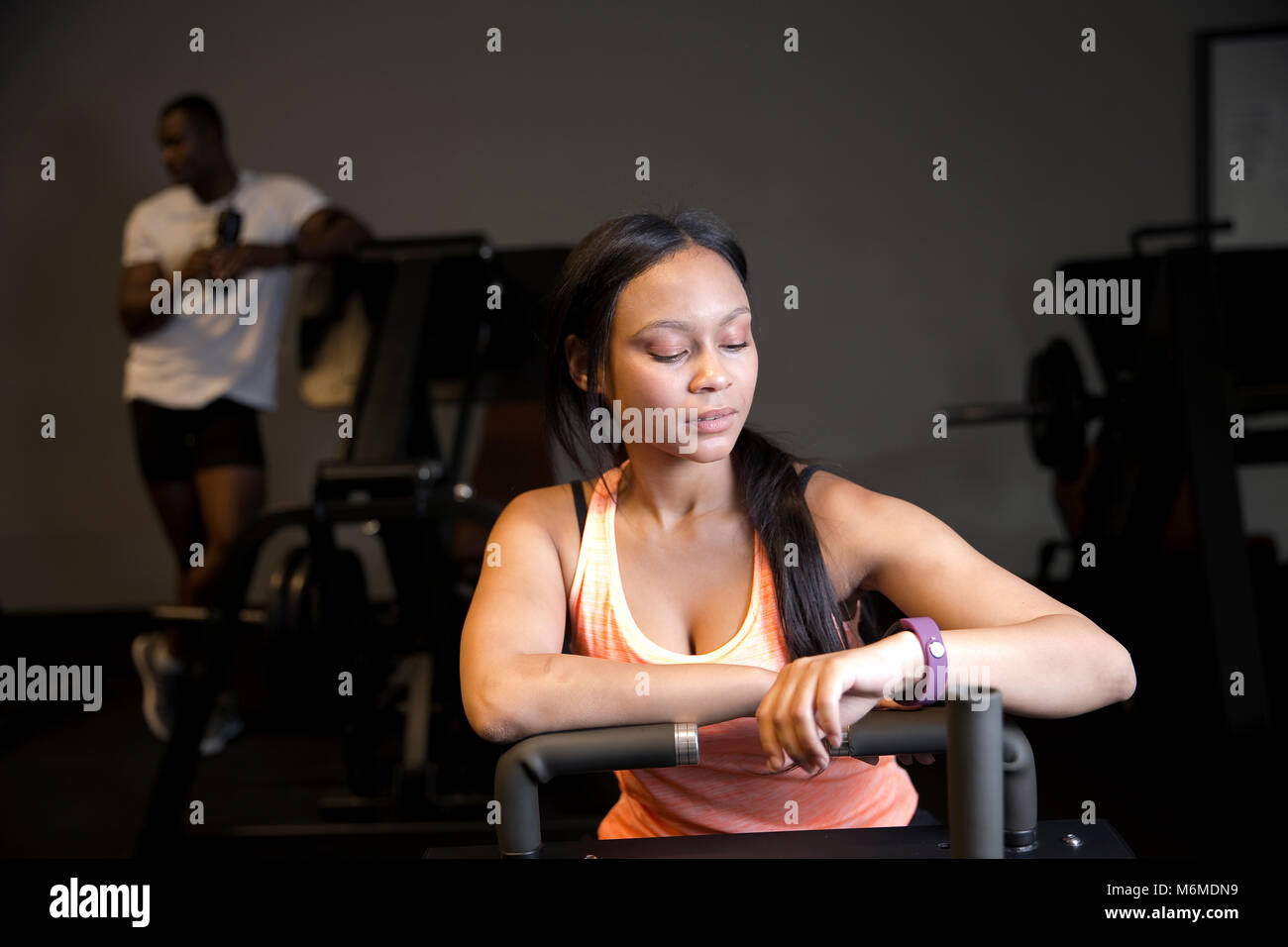 Gemischte Rasse Frau an Smart watch Suchen im Gymnasium Stockfoto