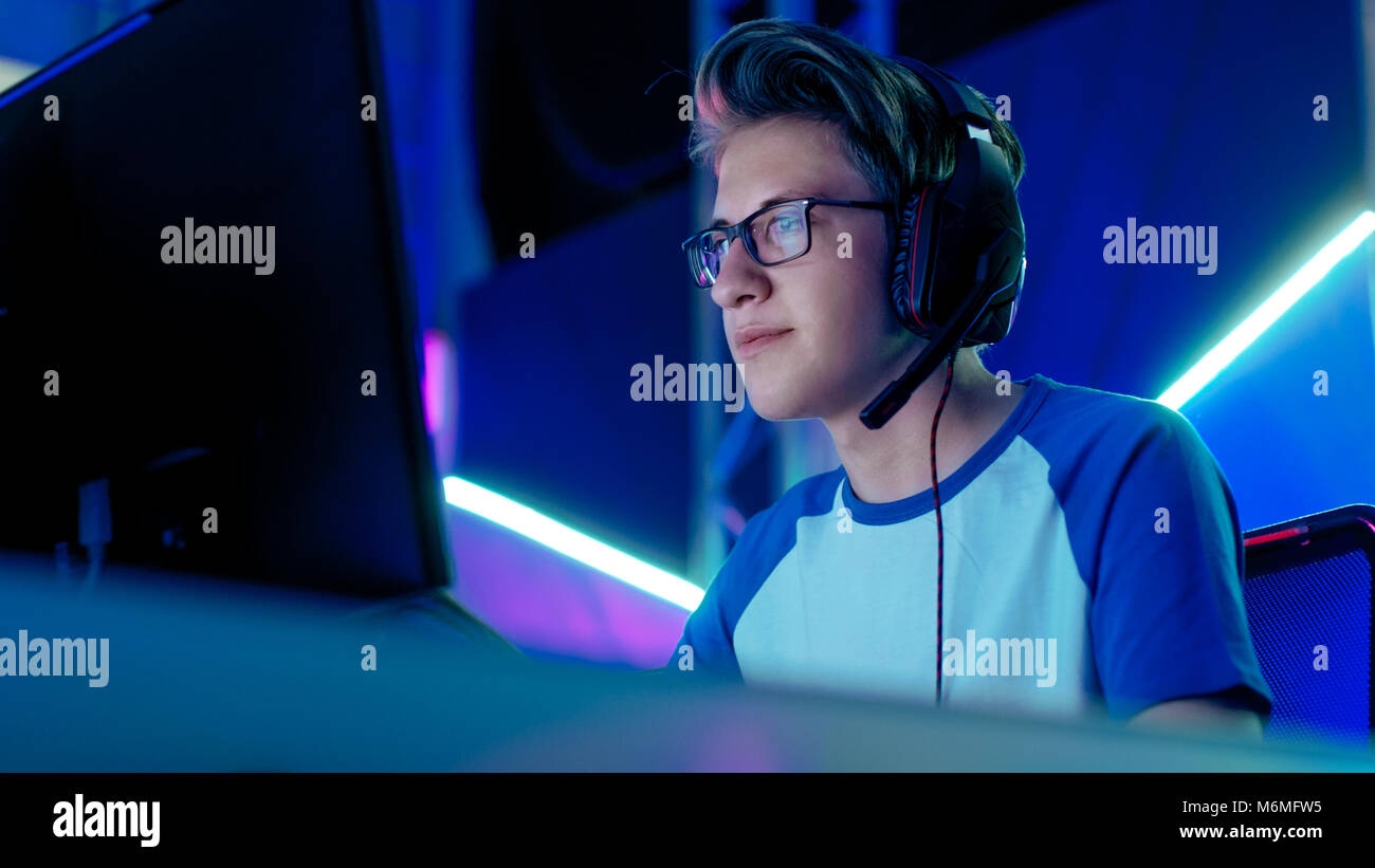 Teenager Jungen Gamer spielt in den konkurrierenden Video Games, eSports Turnier/Internet Cafe. Er trägt eine Brille und Kopfhörer mit Mikrofon. Stockfoto