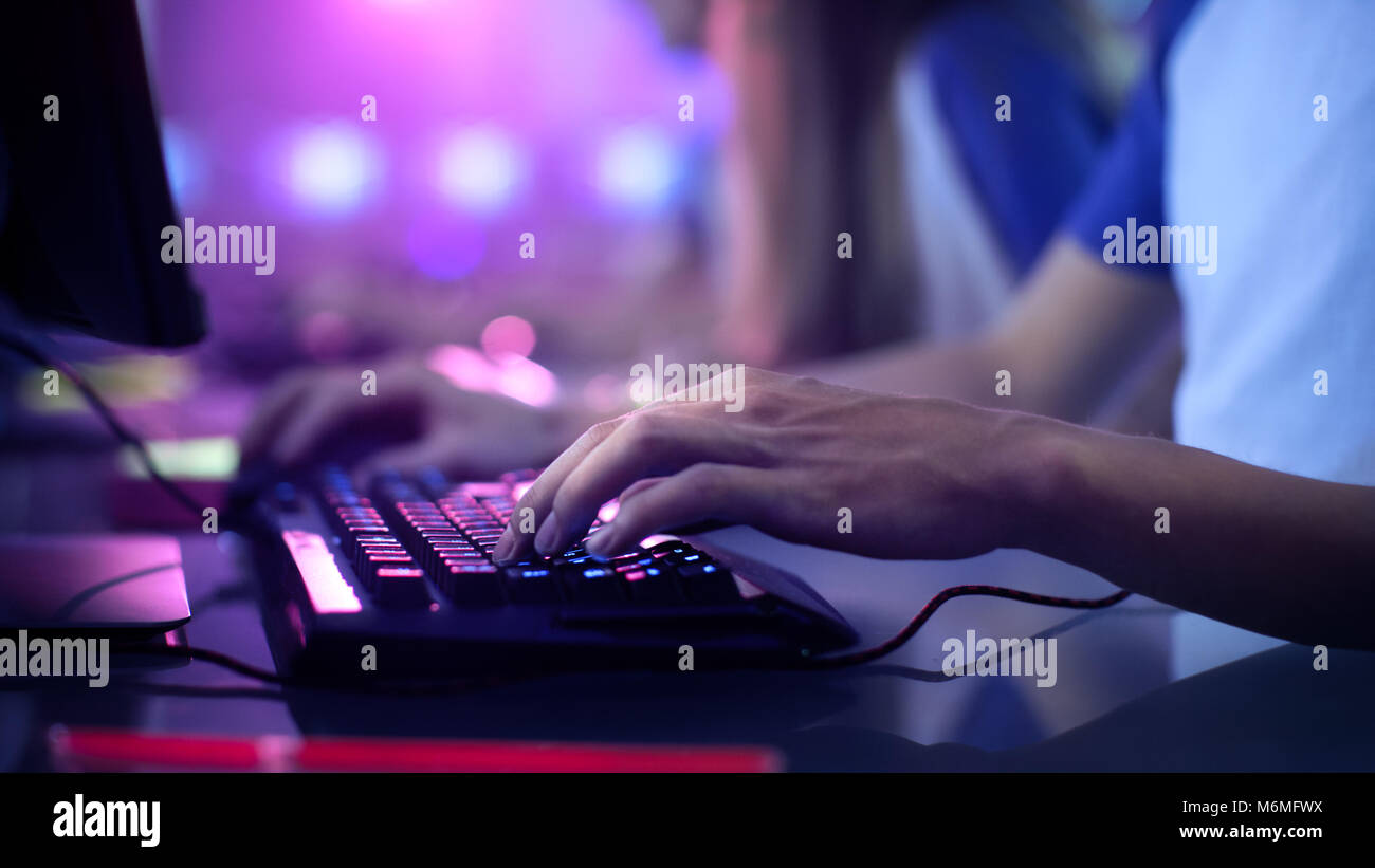 Close-up auf der Gamer Hände auf der Tastatur, Tasten, Spielen MMO-Spiele Online. Hintergrund Leuchtet mit Neonlicht. Stockfoto