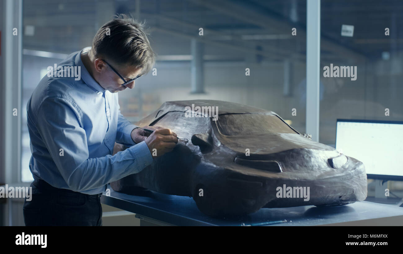 Grauhaariger Automotive Designer formt futuristischen Auto Modell aus Plastilin Ton mit Draht. Er arbeitet in einem speziellen Studio in ein großes Auto, entfernt Stockfoto