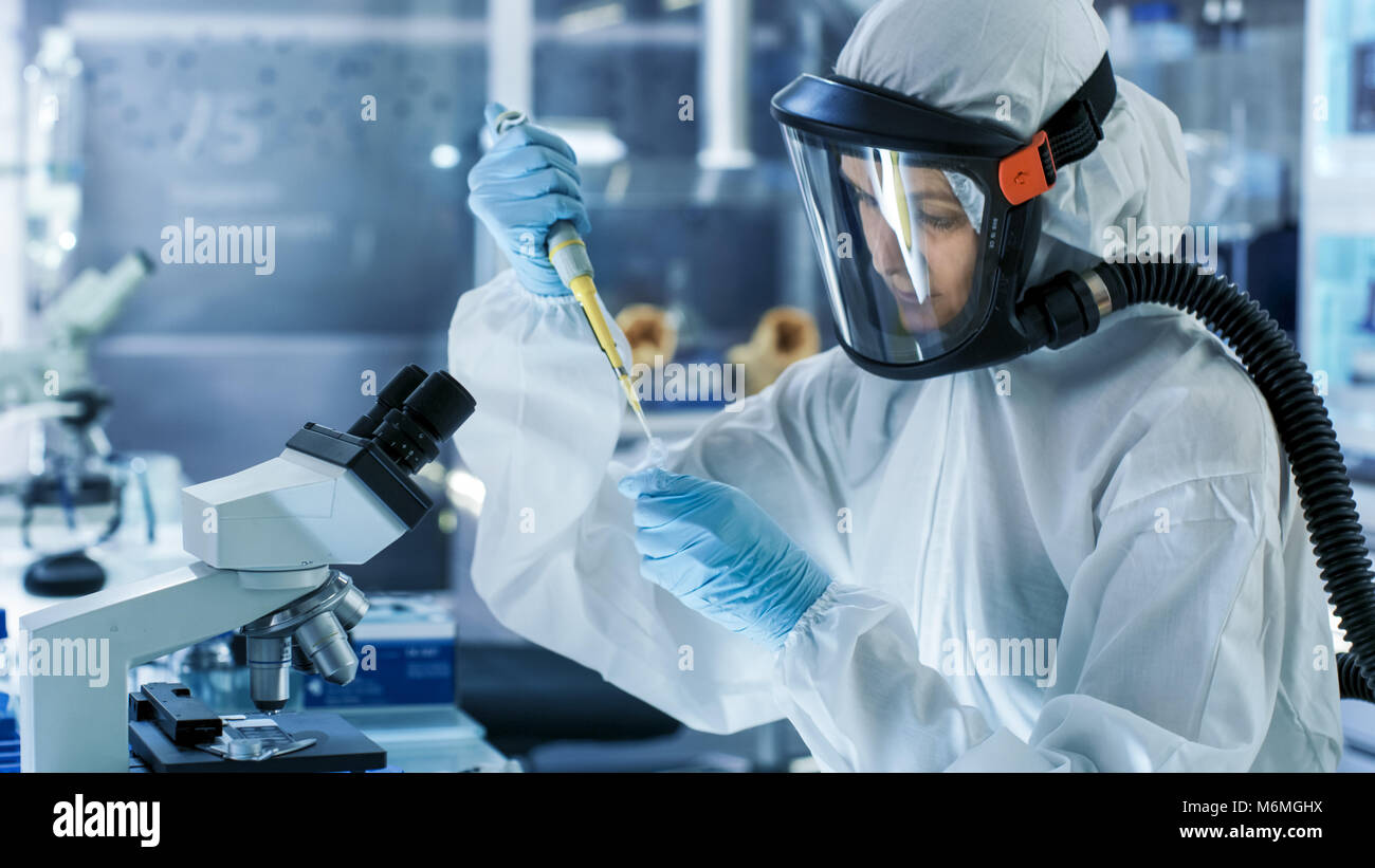 Medizinische Virologie Wissenschaftler arbeitet in einem Gefahrgut-Anzug mit Maske, nutzt sie Pipette. Sie arbeitet in einem sterilen High-Tech-Labor Stockfoto