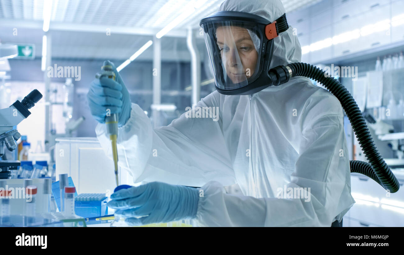 Medizinische Virologie Wissenschaftler arbeitet in einem Gefahrgut-Anzug mit Maske, nutzt sie Pipette. Sie arbeitet in einem sterilen High-Tech-Labor Stockfoto