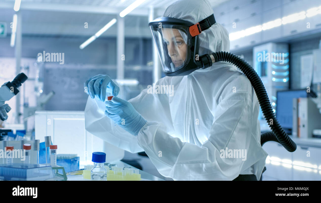 Medizinische Virologie Wissenschaftler arbeitet in einem Gefahrgut-Anzug mit Maske, nutzt sie Pipette. Sie arbeitet in einem sterilen High-Tech-Labor, Forschung Fac Stockfoto