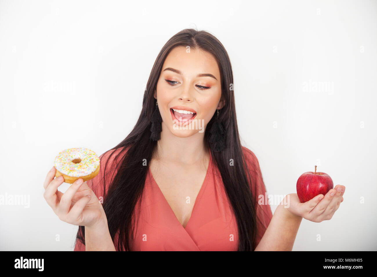 Hübsches junges Mädchen mit einem Gewicht von bis Essen Optionen Donut oder Apple. Stockfoto