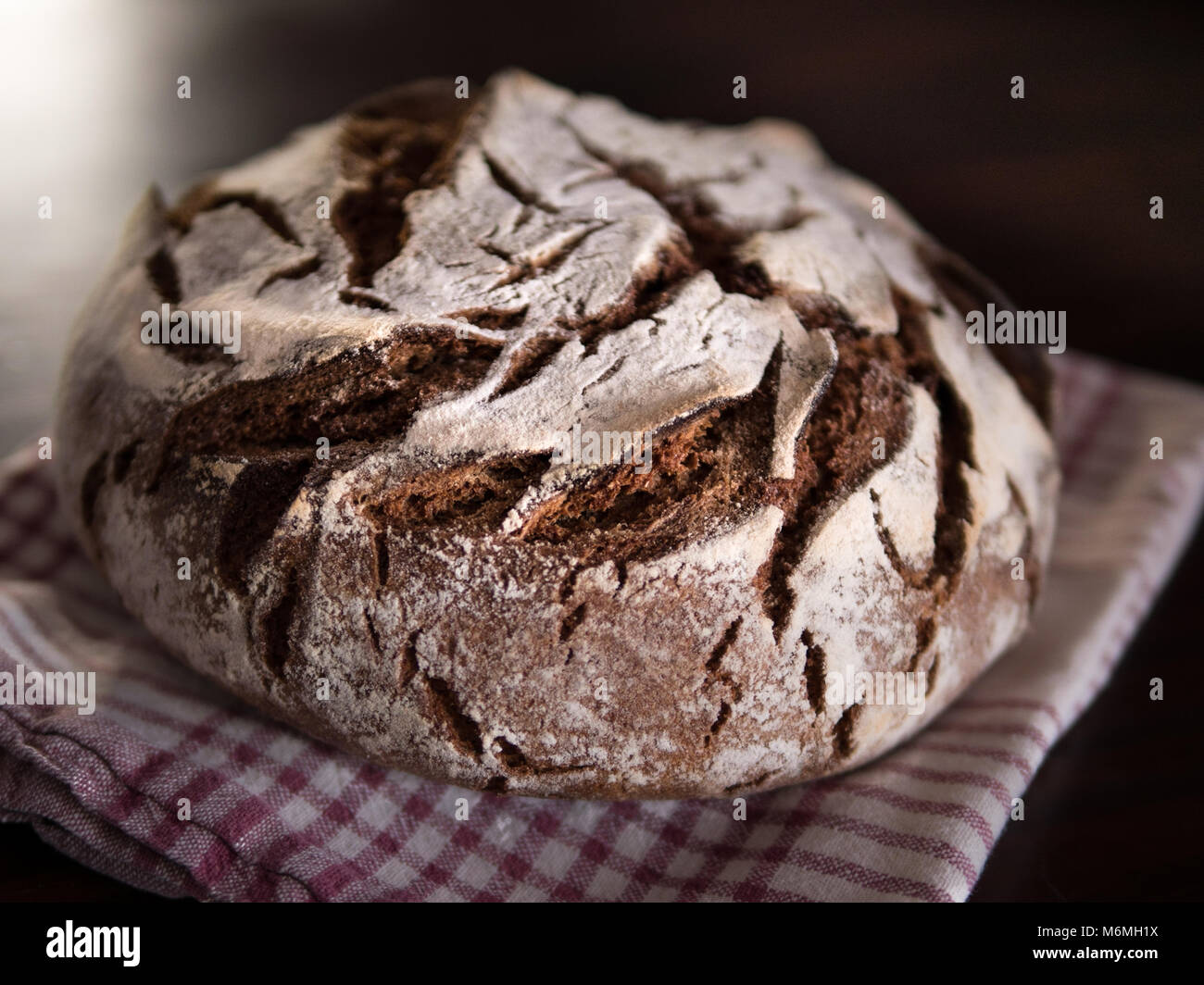 Nahaufnahme von einem frisch gebackenen Runde coutry Brot auf einem Handtuch und Holztisch Stockfoto