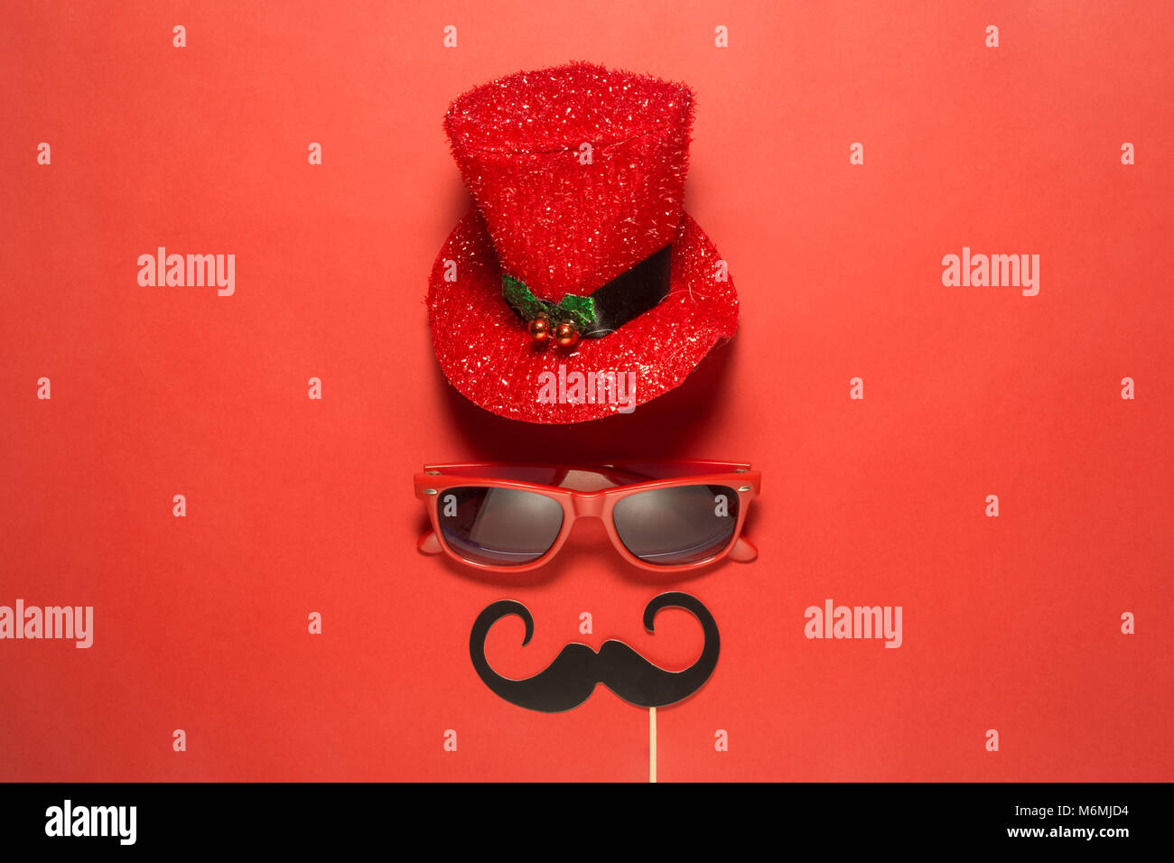 Hipster Retro Vintage exzentrische Mann mit dem roten Zylinder Hut und Sonnenbrille Schnurrbärte abstrakt gegen roten Hintergrund minimalen Begriff. Stockfoto
