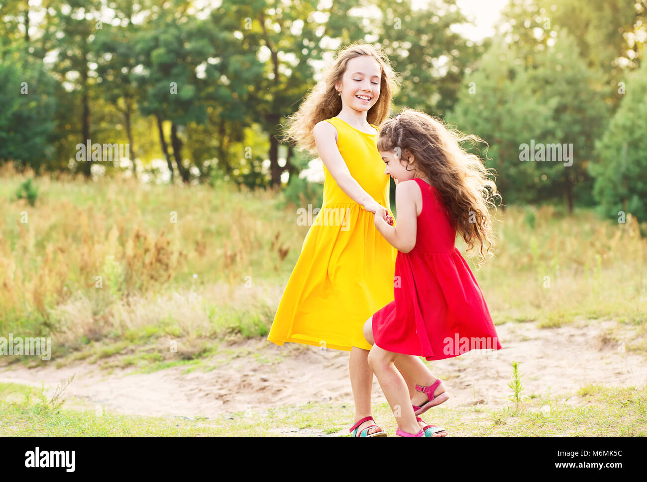 Zwei glückliche kleine Mädchen umarmen und Tanzen an sonnigen Sommertag Stockfoto
