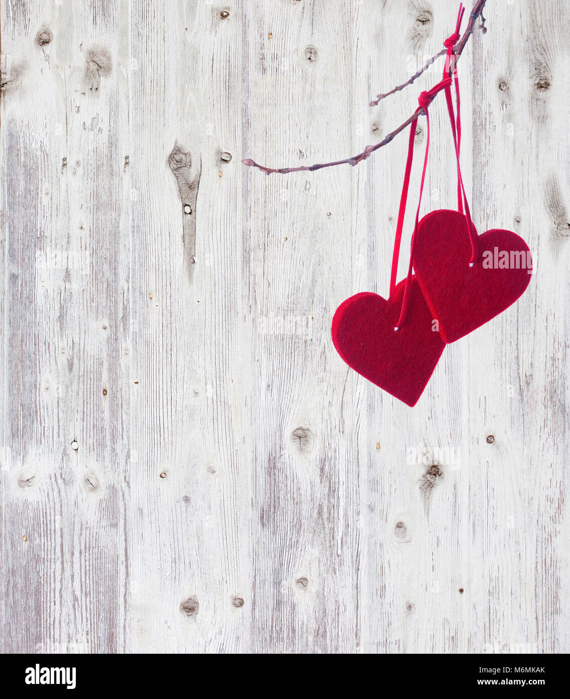 Zwei rote Herzen, hängend an einer Niederlassung über die alten hölzernen Hintergrund. Stockfoto
