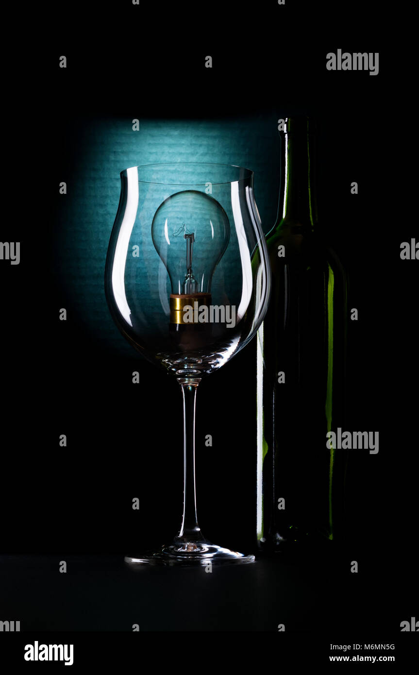 Einem stimmungsvollen, atmosphärischen shot Wein Glas und Flasche. Einen tungsten Glühbirne, die Wahl oder Optionen darstellen könnte. Stockfoto