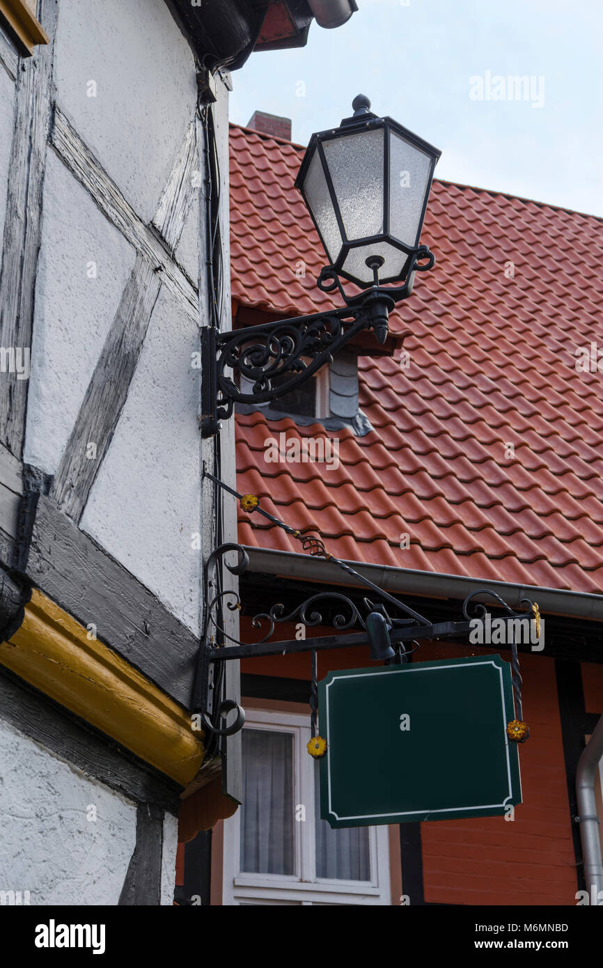 Dekoratives Gusseisen Laterne und ein Zeichen an der Wand der Deutschen Fachwerkhäuser auf dem Hintergrund von Ziegeldächern. Wernigerode. Deutschland Stockfoto