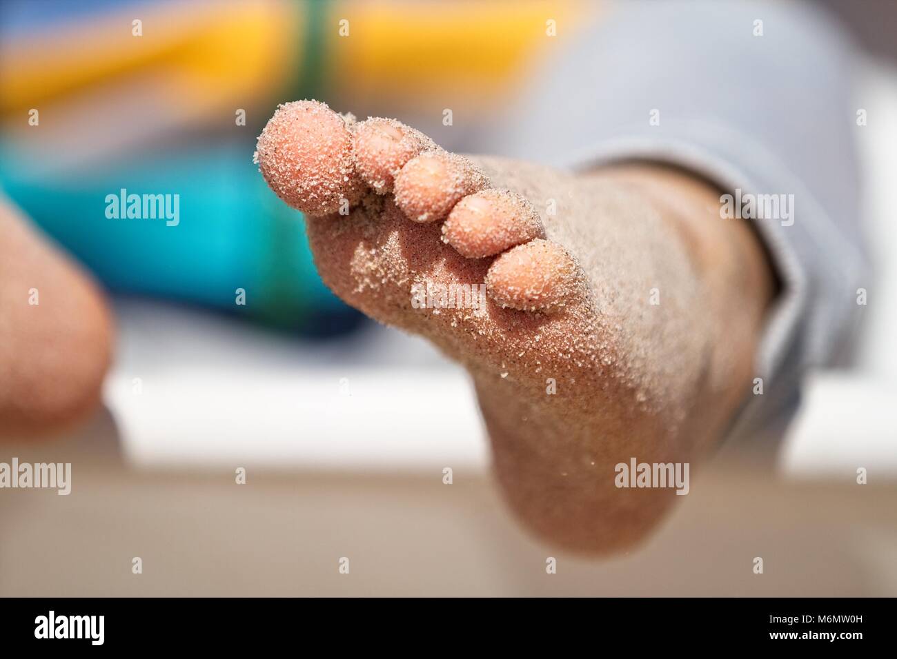 Gerne barfuß auf Sandstrand. Füße im Sand. Sonnig. Geringe Tiefenschärfe. Stockfoto