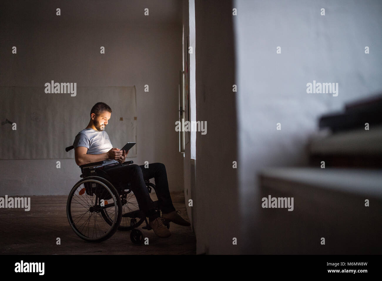 Mann im Rollstuhl arbeiten mit Tablet. Stockfoto
