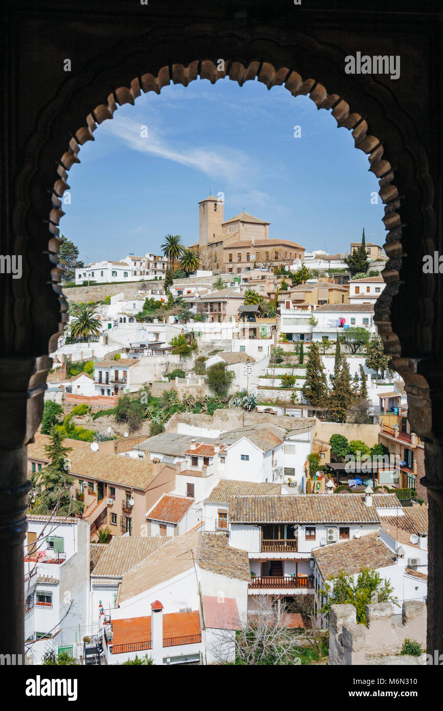 Granada, Andalusien, Spanien. Unesco Viertel Albaicin und Kirche von San Cristóbal umrahmt von einer maurischen Fenster aus dem 15. Jahrhundert Dar al-Horra pala aufgeführt Stockfoto