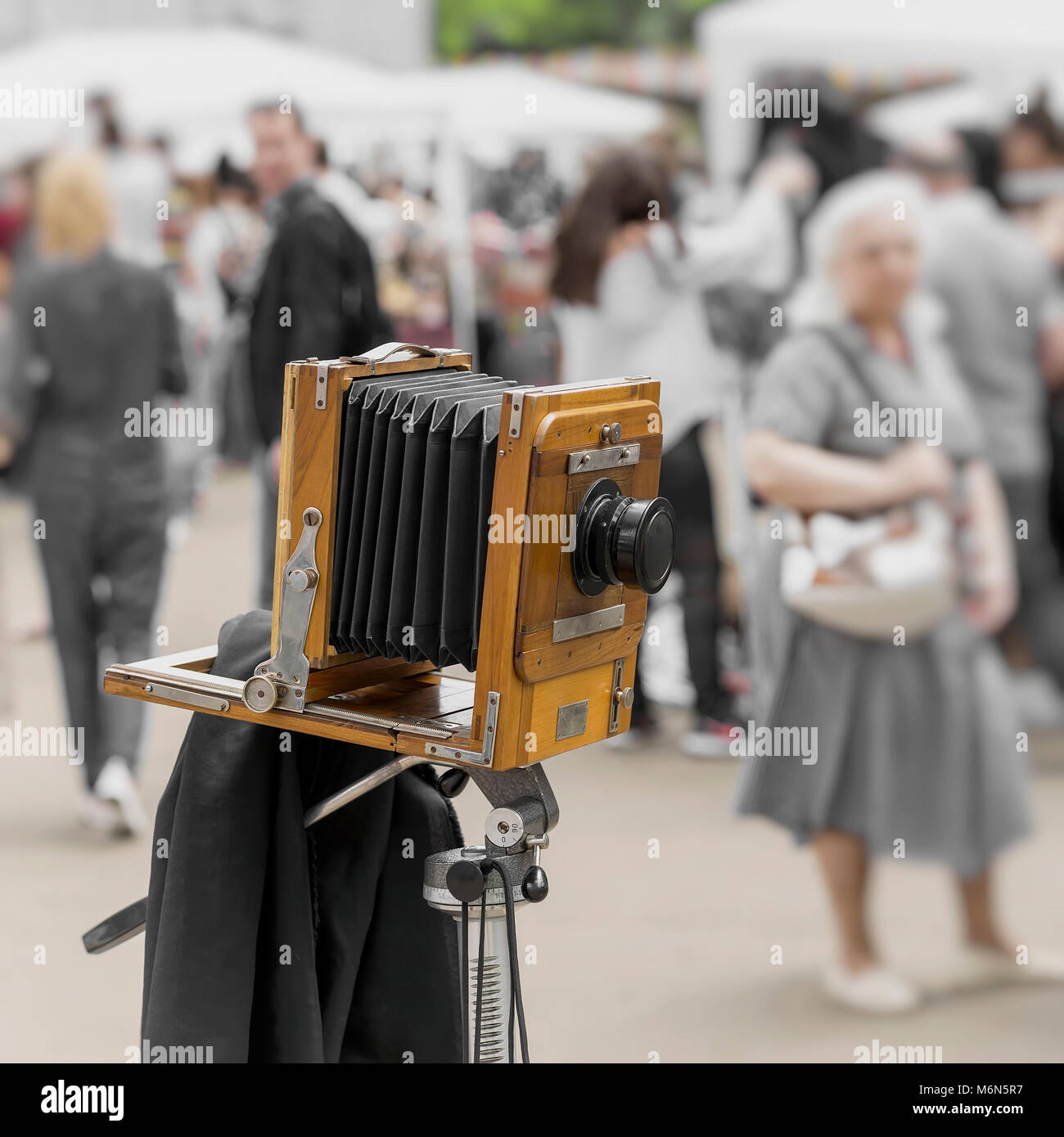 Vintage photo Holz- Kamera auf Stativ gegen den Hintergrund der wandern Menschen in den Park. Mit Retro Stil verarbeitet. Foto-, Kino- Konzept und andere Antiquitäten Stockfoto