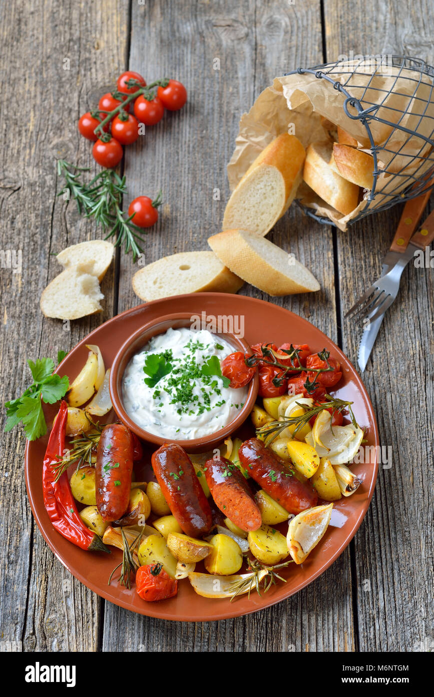 Spanisches essen: gebackene heiße Chorizo Wurst mit Rosmarin Gemüse und mediterrane Kräuter Quark Stockfoto