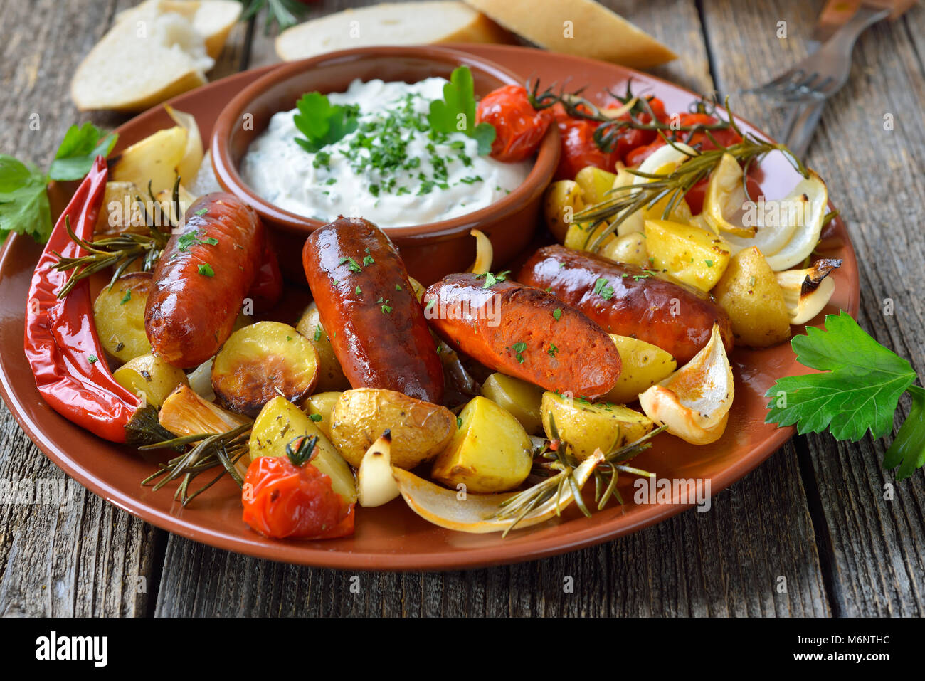 Spanisches essen: gebackene heiße Chorizo Wurst mit Rosmarin Gemüse und mediterrane Kräuter Quark Stockfoto