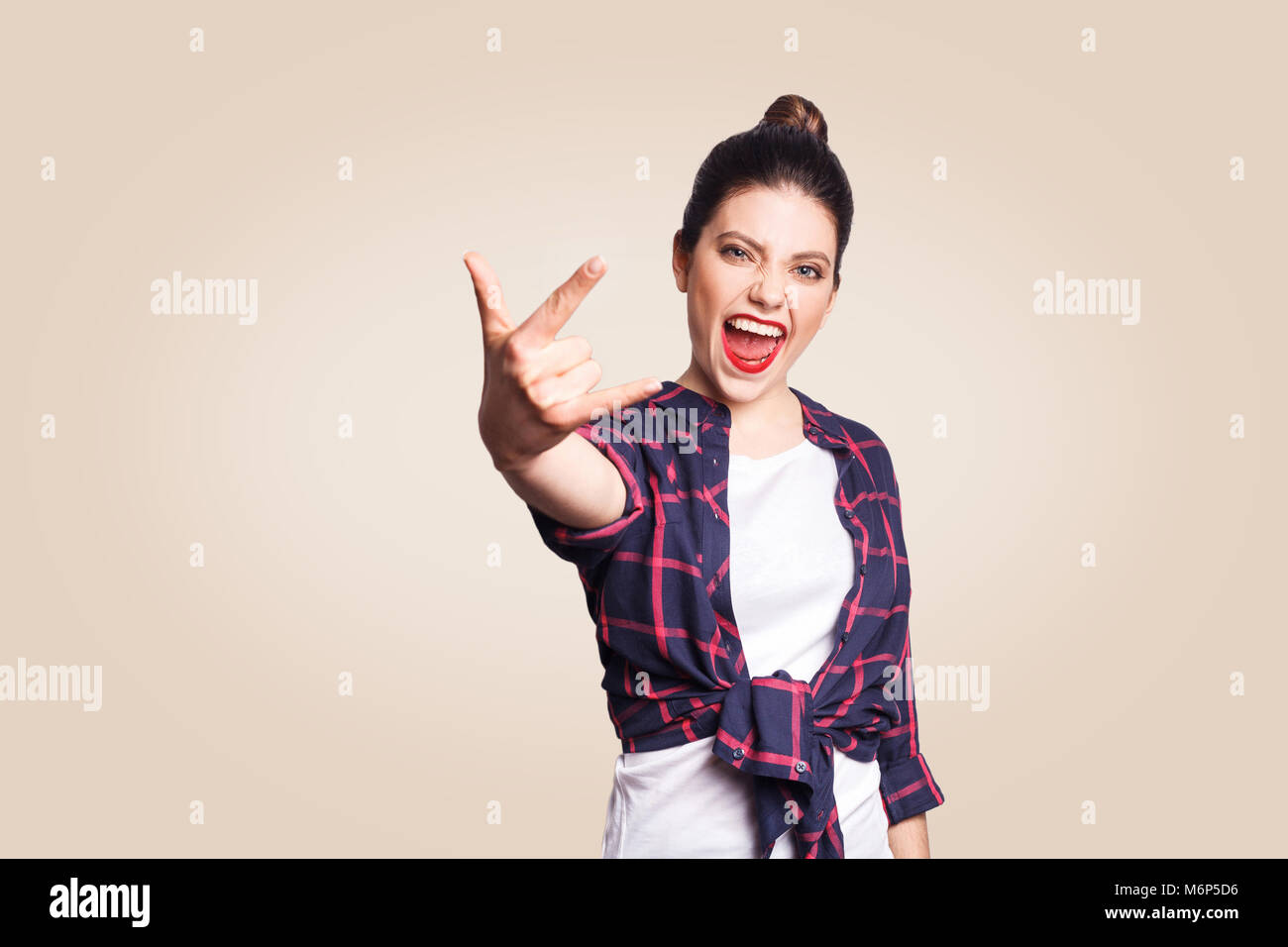 Rock unterzeichnen. Gerne lustig toothy Smiley junge Frau mit Rock mit Fingern. studio Schuß auf beigen Hintergrund. Konzentrieren Sie sich auf das Gesicht. Stockfoto