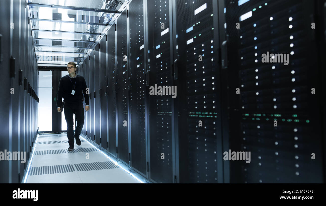 IT-Techniker Holding Notebook und gehen durch Data Center voller Arbeit Rack Servern. Stockfoto
