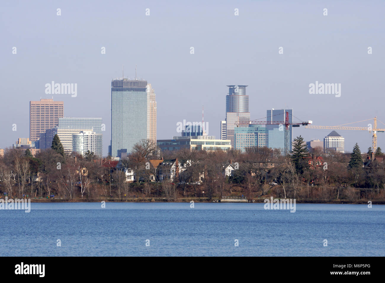 Minneapolis Minnesota Skyline. Closeup Wolkenkratzer Turm über der Baumgrenze und schönen blauen See im Winter. Gebäude Downtown Financial District Bank Stockfoto