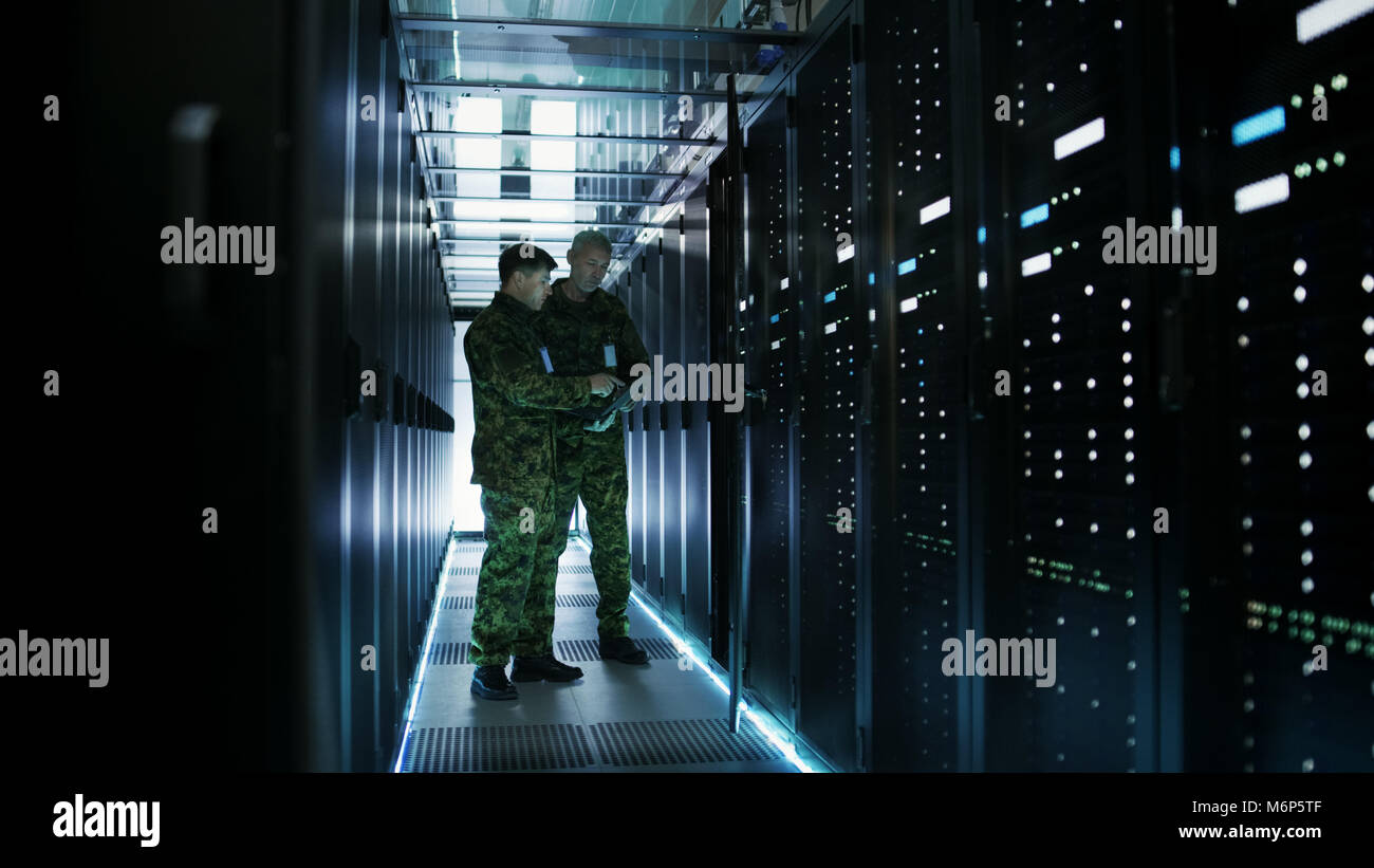 Im Rechenzentrum zwei militärische Männer arbeiten mit offenen Server Rack. Man hält Militärische Edition Laptop. Stockfoto