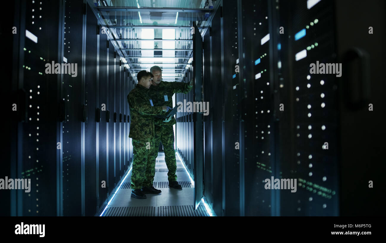 Im Rechenzentrum zwei militärische Männer arbeiten mit offenen Server Rack. Man hält Militärische Edition Laptop. Stockfoto