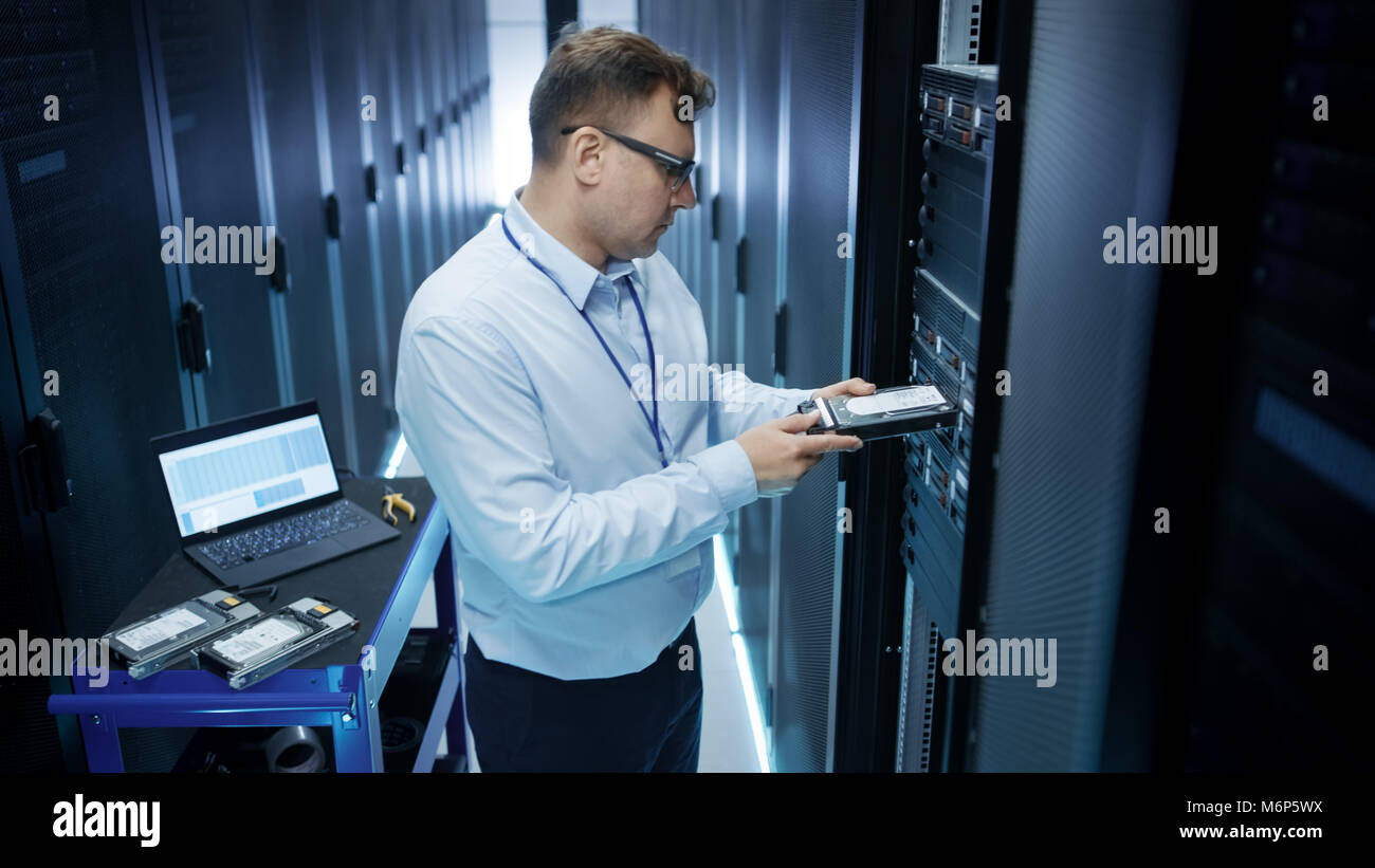 IT-Techniker Installation von Festplatten in das Rack Server. Er arbeitet im Rechenzentrum. Auch nutzt er Laptop. Stockfoto
