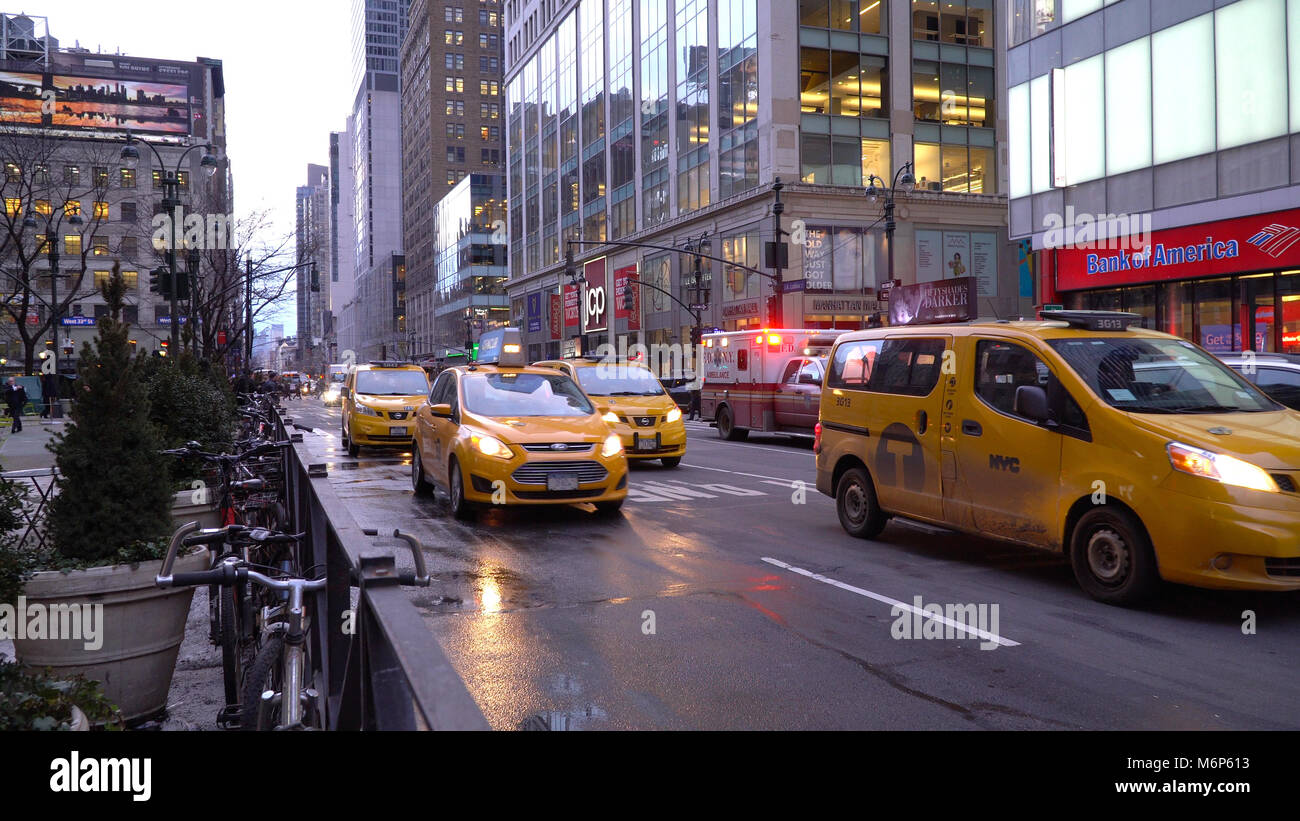 New York City - ca. 2017: FDNY EMS Krankenwagen blinkende Lichter strahlen Sirene Geschwindigkeit durch den Berufsverkehr in Midtown Manhattan. Gelbe Taxi fi Stockfoto