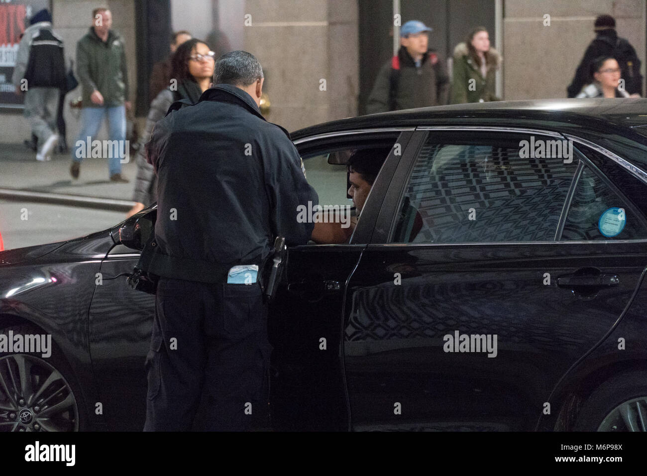 New York City, ca. 2017: Police Officer NYPD zieht über livery Cab Driver und prüft, Lizenz- und Identifikation. Nacht Zeit während der Rush Stockfoto