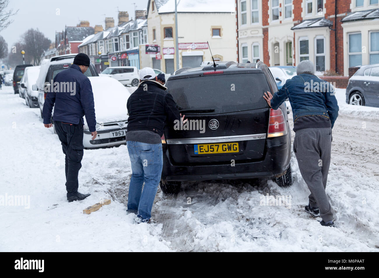 Freunde helfen einem Freund von seinem Auto drücken in tiefen Schnee Stockfoto