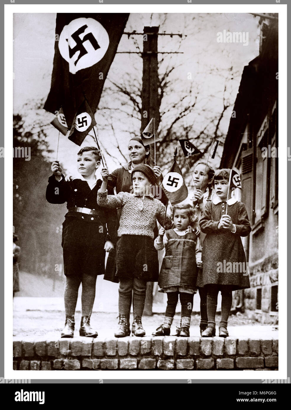 Gruppe der verwirrte Junge Kinder winken NS-Hakenkreuz Fahnen zur Unterstützung einer lokalen NS-Parade 1930 Saarland Deutschland Stockfoto