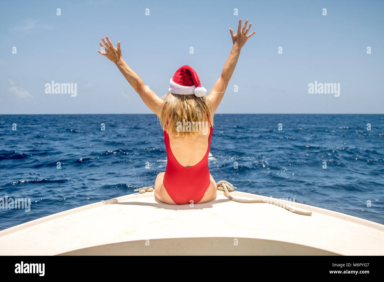 Eine Frau sitzt auf der Vorderseite eines Bootes und genießt die Wintersonne zu Weihnachten. Stockfoto