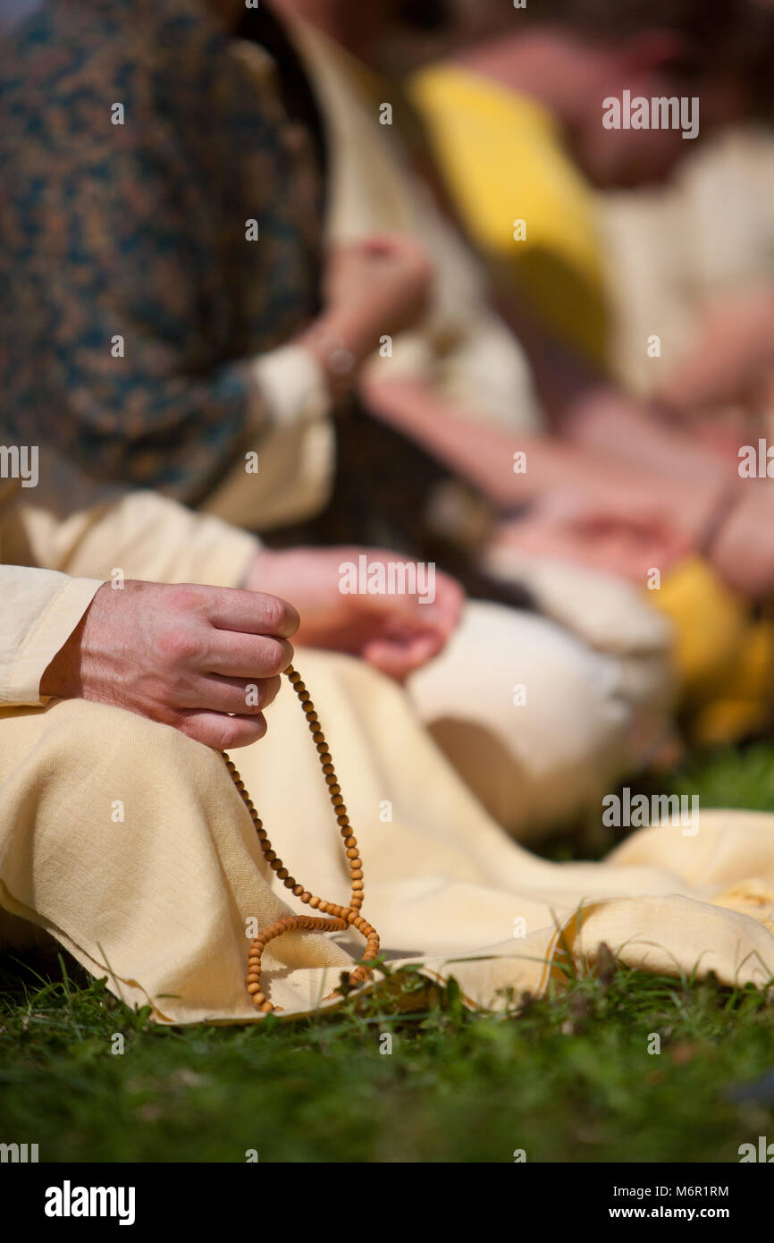 Eine Nahaufnahme an Hand des Menschen üben Meditation mit mala Perlen, ausserhalb auf Gras im Park bei schönem sonnigen Tag. Die Teilnahme an Exerzitien. Stockfoto