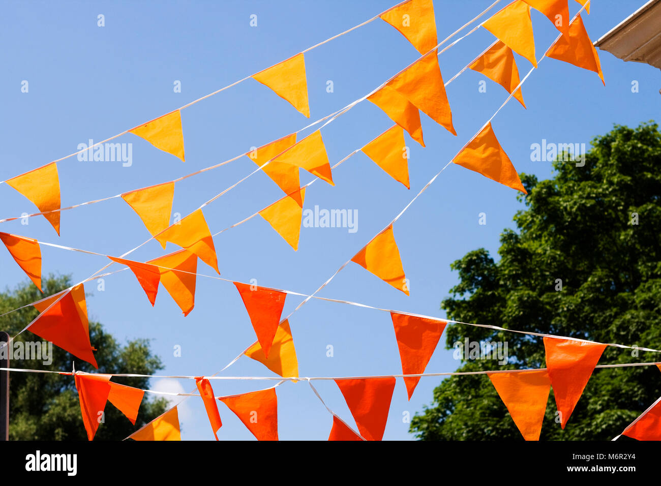 Orange Flaggen hängen außen vor blauem Himmel. (Oft am Königinnentag in den Niederlanden verwendet) Stockfoto