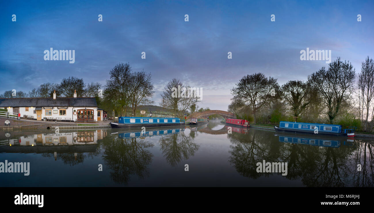 Erstes Licht an Foxton auf dem Grand Union Canal, der treffend benannten Brücke 61 Pub sowie narrowboats und einem Buckel-zurück-Brücke. Stockfoto