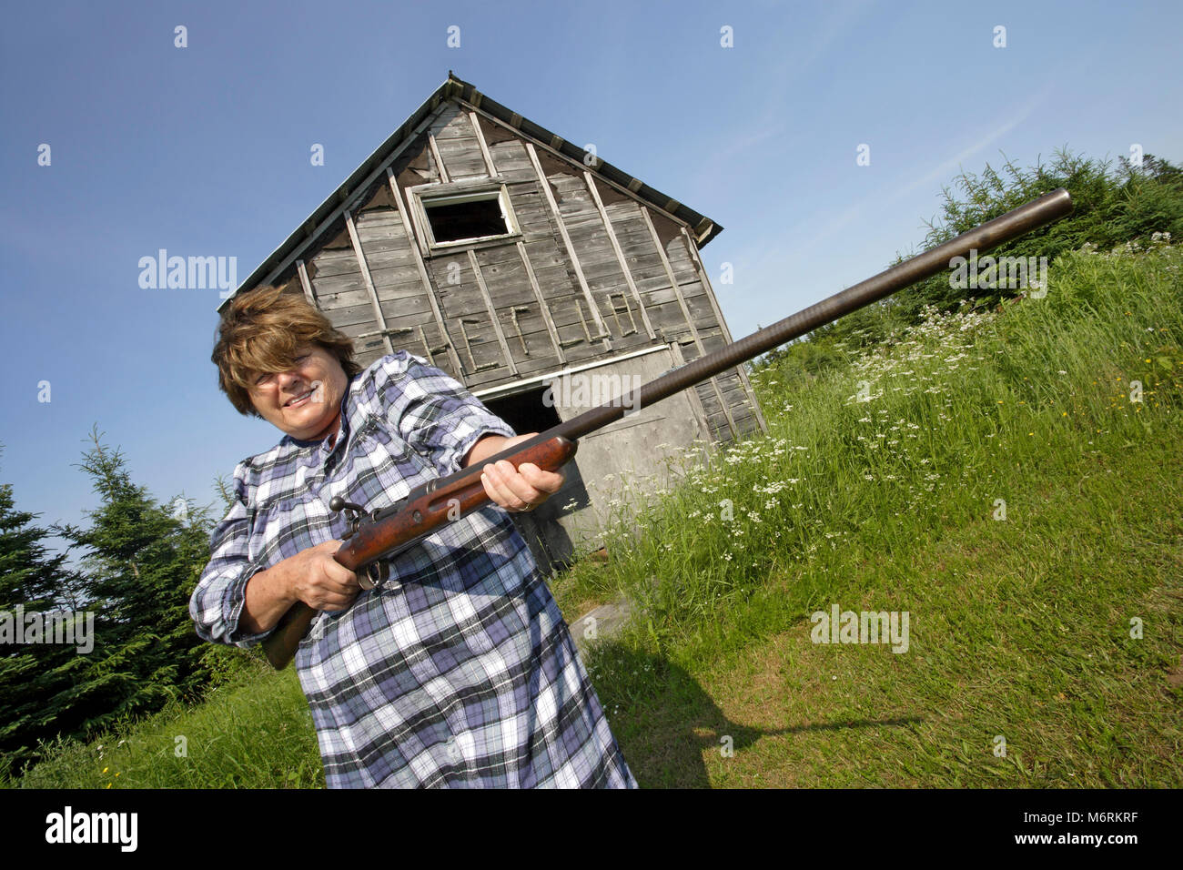 Foto von eine ältere Frau mit einem großen Gewehr. Stockfoto