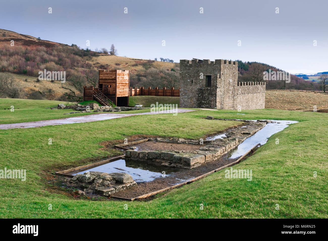 Roman fort: Vindolanda, Blick auf die rekonstruierten Turm Abschnitt der Hadrian's Wall mit ausgegraben Wassertank Notunterstände im, Northumberland, England, Großbritannien Stockfoto