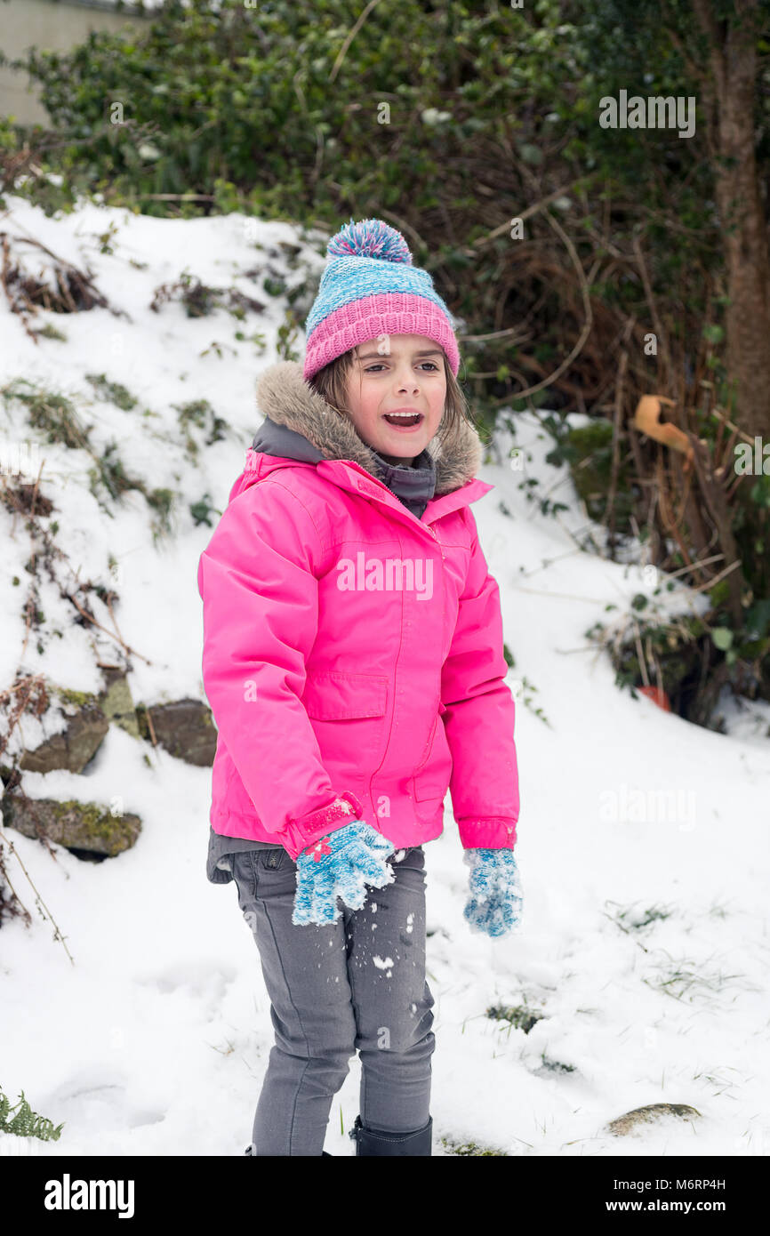 Süßes kleines Mädchen Spaß im Schnee. Weibliches Kind spielen Im schneereichen Winter Wetter trägt einen rosa Fell und blaue pompom hat Stockfoto