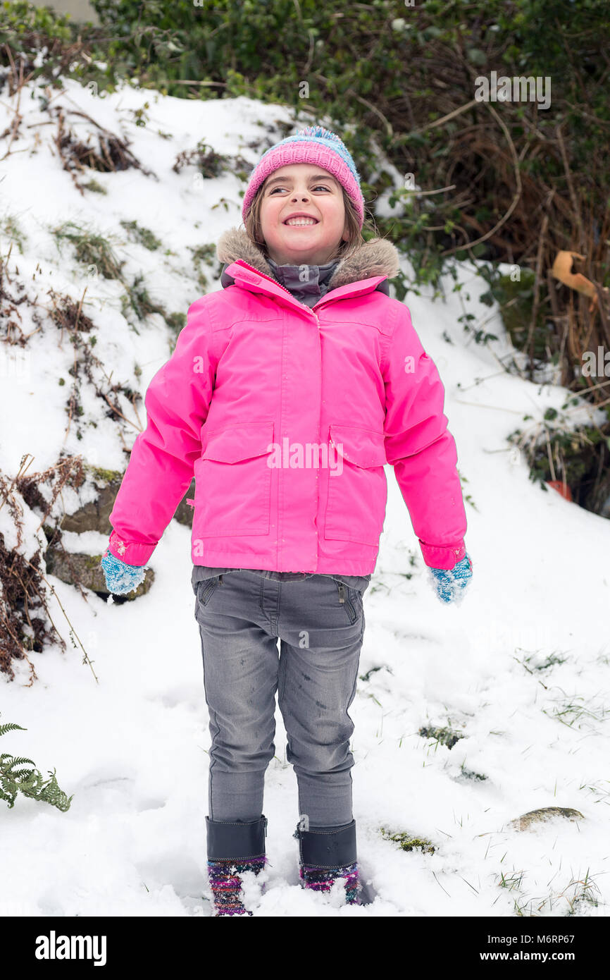 Süße kleine Mädchen spielen im Schnee trägt einen rosa Fell. Volle Länge vertikale Portrait Stockfoto