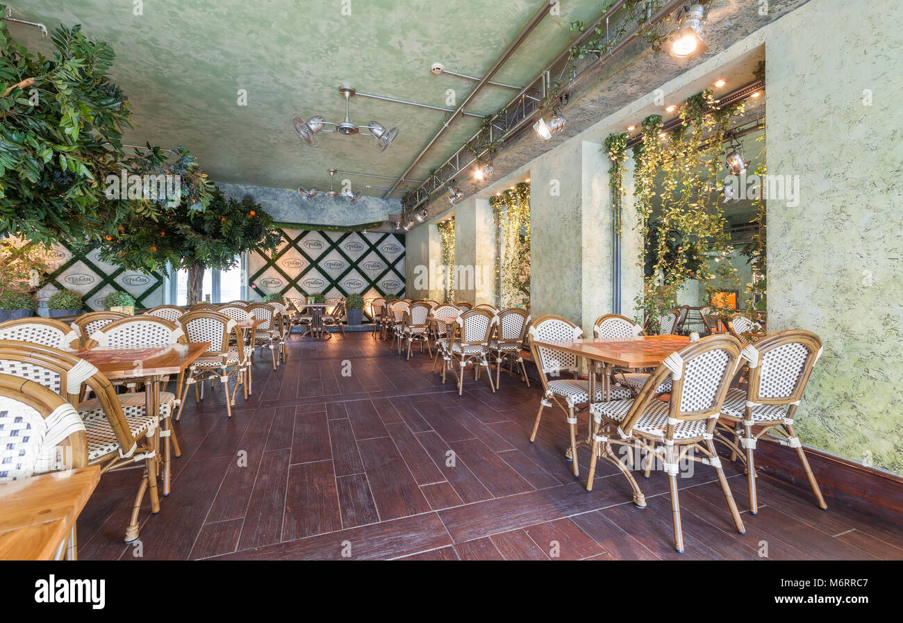 Moskau - Juli 2014: Chain Home Cooking Restaurant "GRABLI". Der Innenraum des Konzept der Gartenkunst Stil. Holztische mit Korbstühlen Stockfoto