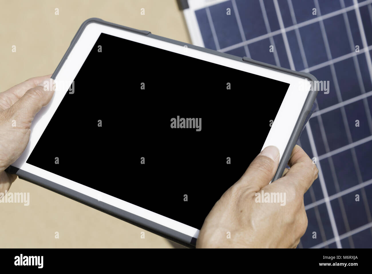 Die Hände einer Frau bedienen ein elektronisches Tablet zur Verwaltung von Solarpaneelen, das über einen schwarzen Bildschirm für anpassbare Texte oder Grafiken verfügt. Nachhaltigkeit Stockfoto